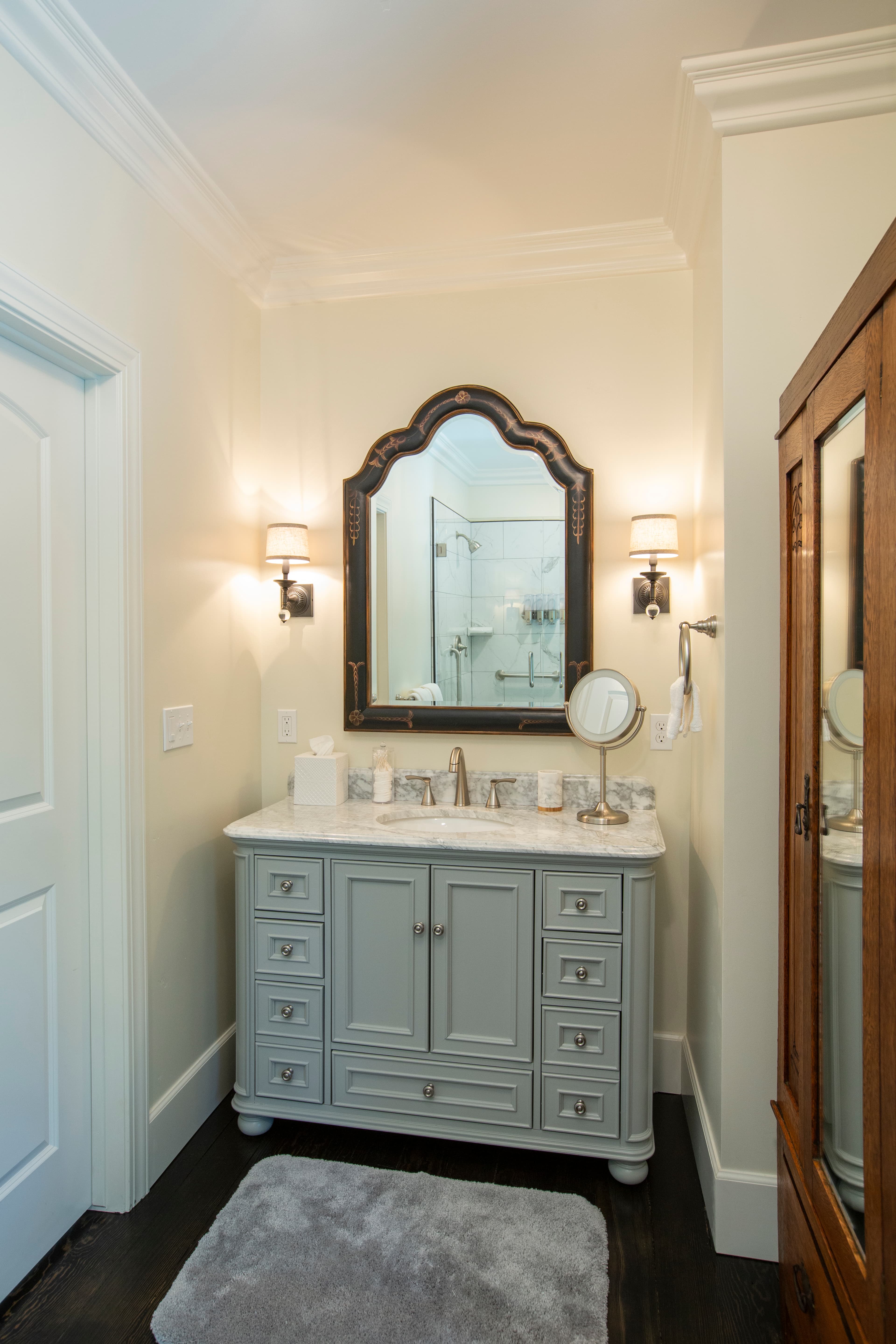 A modern bathroom featuring a light gray vanity with a marble countertop, a large mirror, and stylish wall sconces.