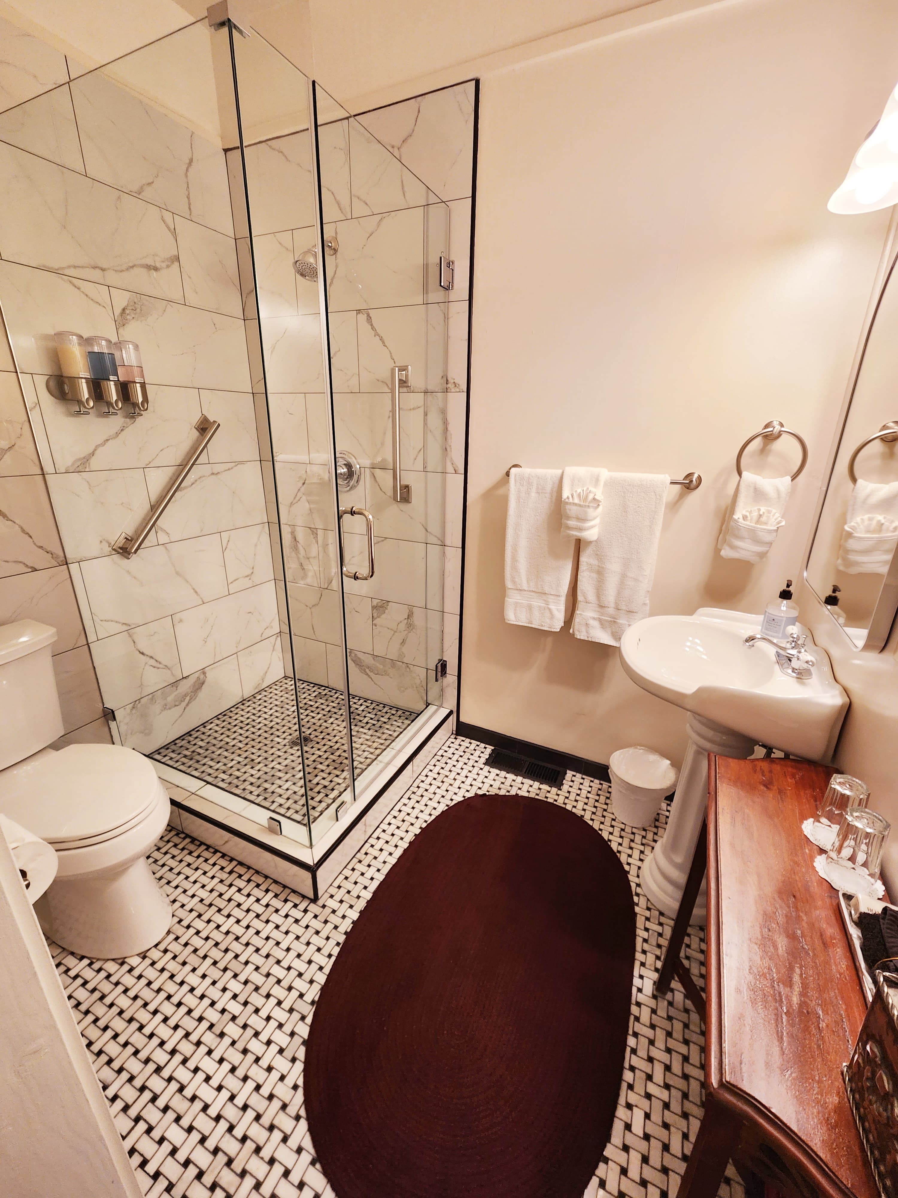 A stylish bathroom featuring a glass shower, modern fixtures, and patterned tile flooring.