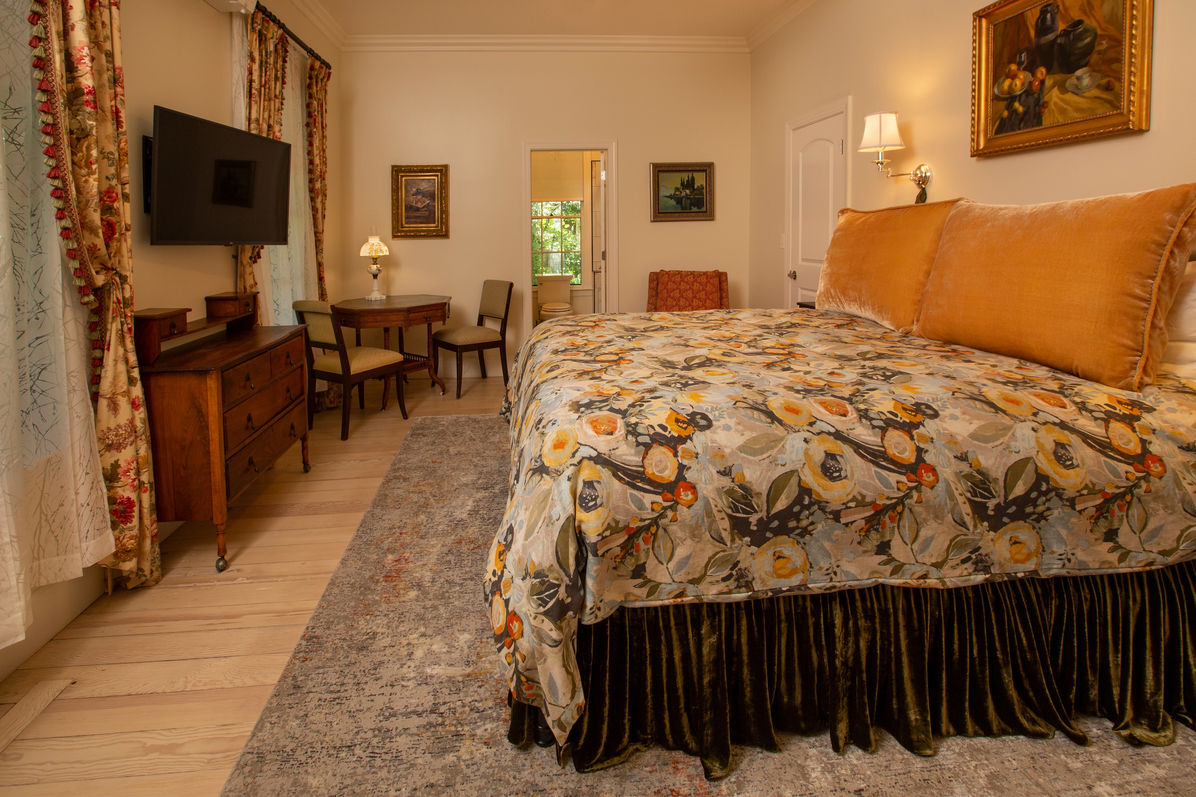 A cozy bedroom featuring a floral-patterned bedspread, wooden furniture, and soft lighting.