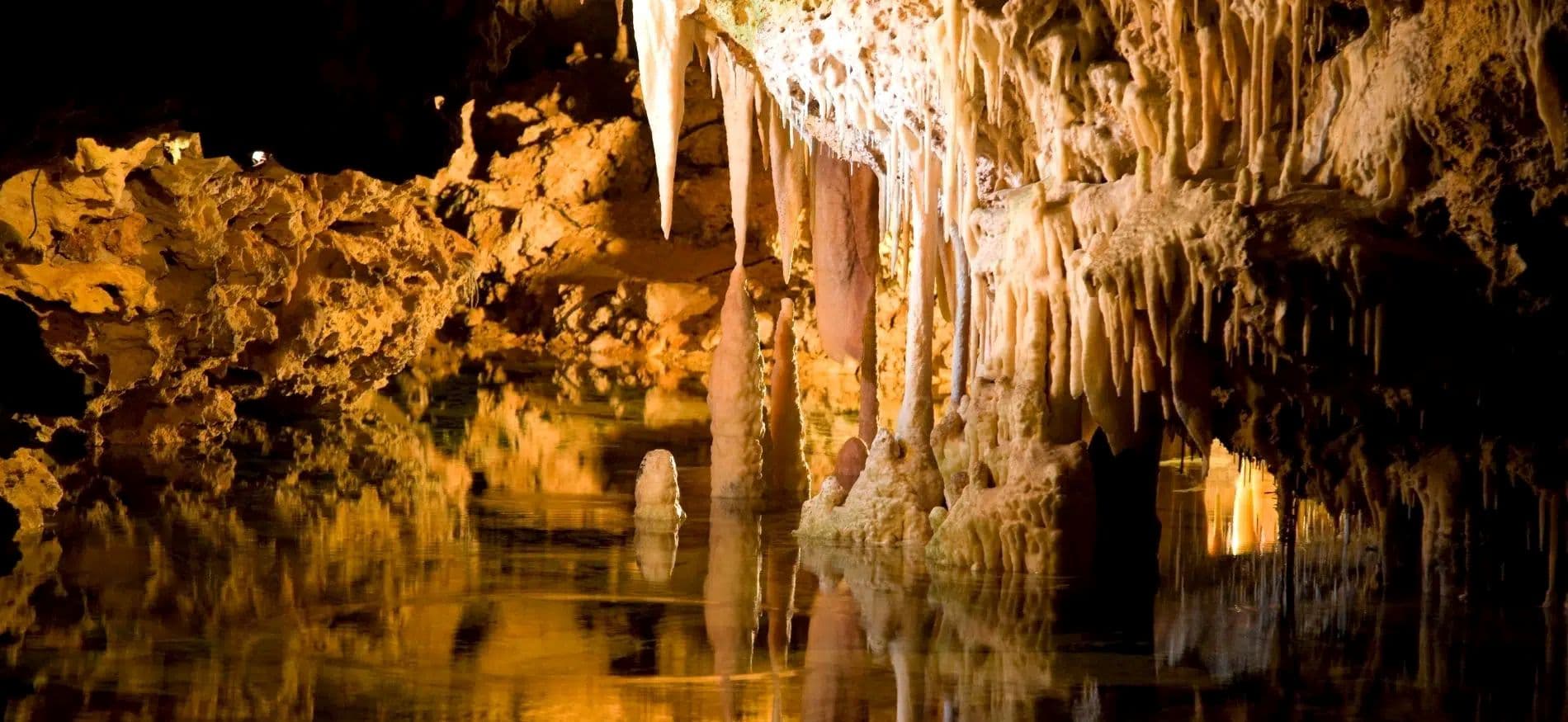The inside of a cavern with water at the bottom and stalactites and stalagmites all around. The inside of a cavern with water at the bottom and stalactites and stalagmites all around.